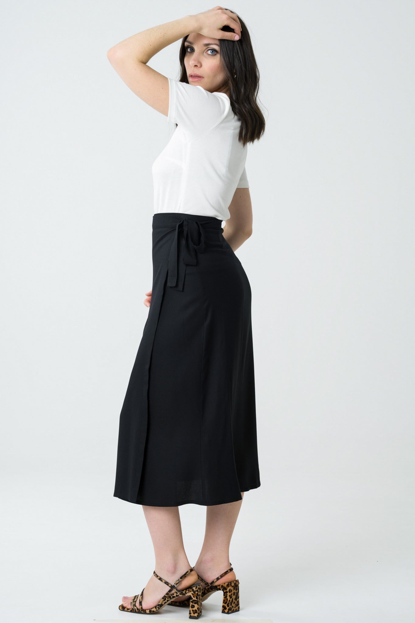 Jupe portefeuille noire mi-longue en viscose Ecovero, fabriquée au Portugal, avec une coupe asymétrique et un tissu doux pour une silhouette moderne et responsable.