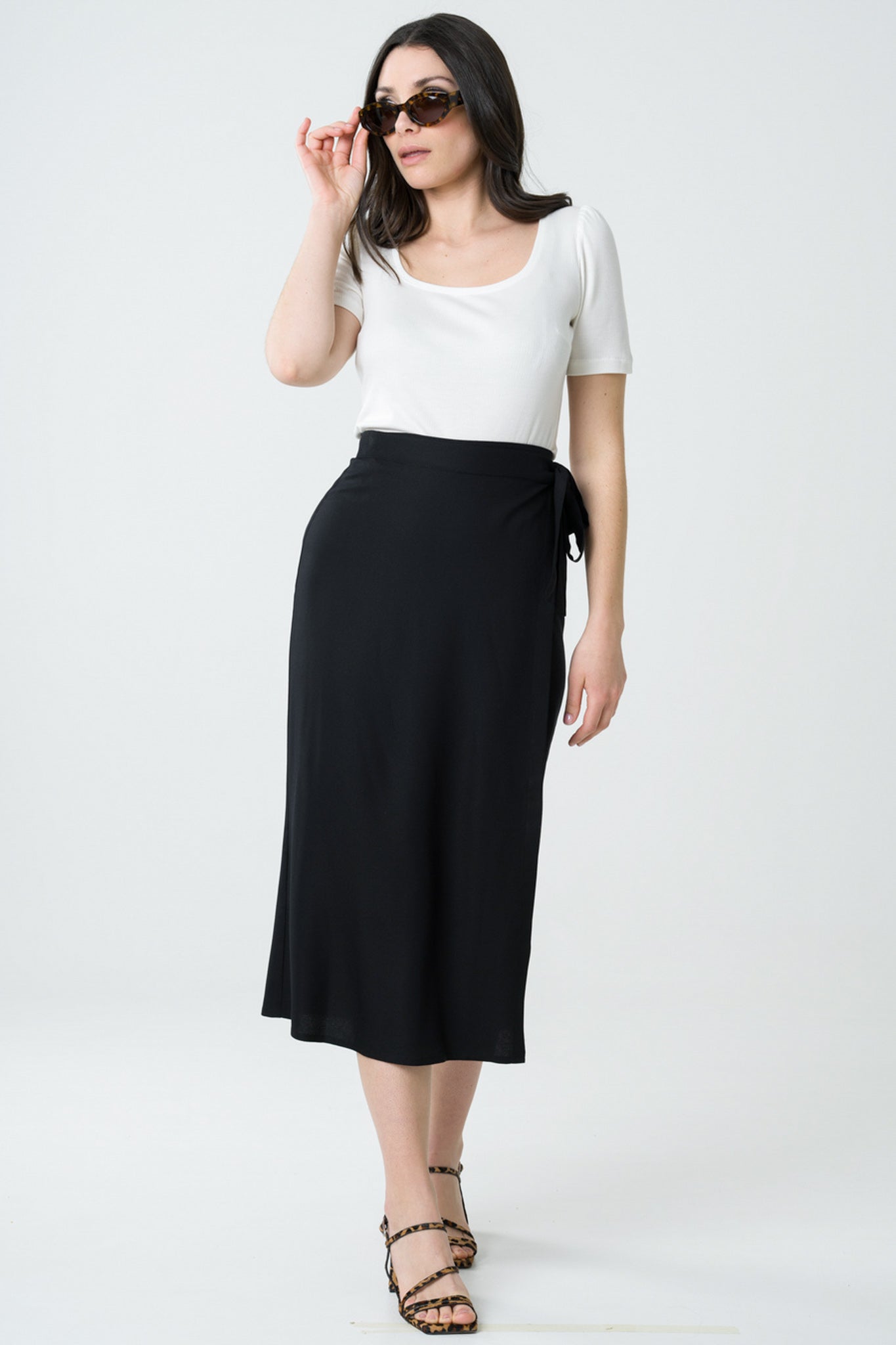 Jupe noire portefeuille mi-longue en viscose Ecovero, fabrication éthique au Portugal, offrant une allure chic et fluide avec un tissu respectueux de l'environnement.