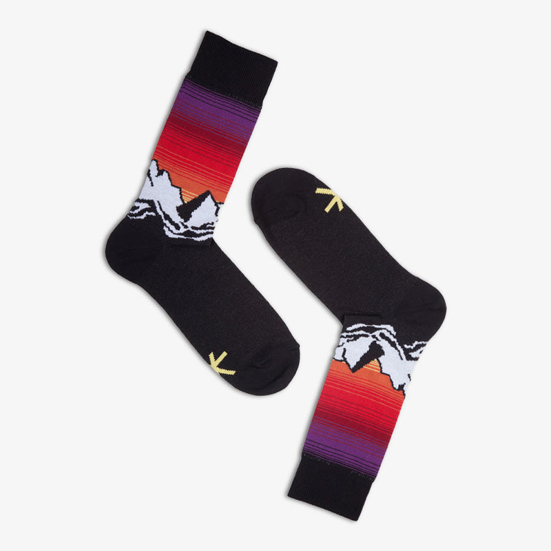 Ein Paar schwarze Socken mit weissen Bergen und rötlichem Himmel