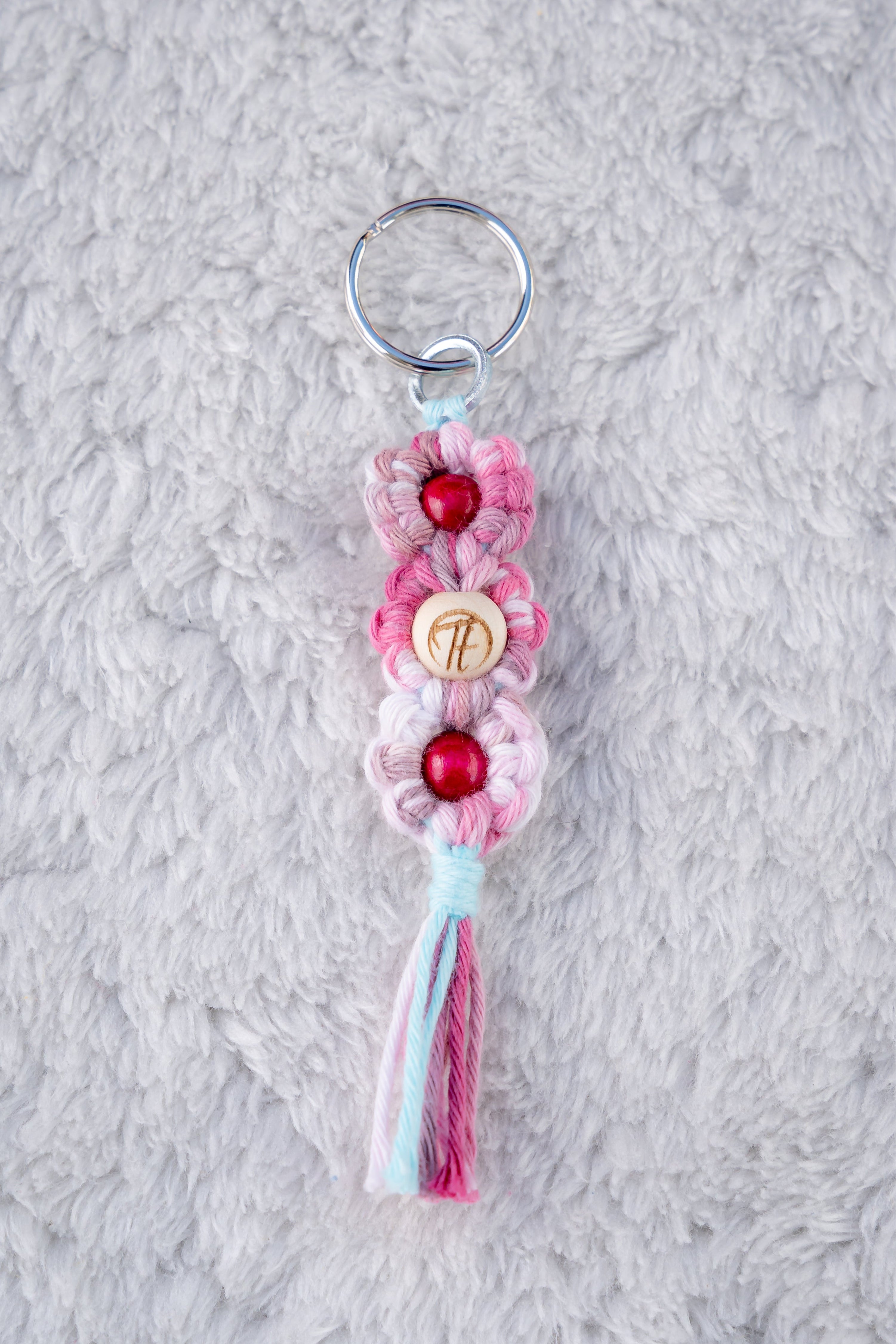 Schöner Makramee Schlüsselanhänger geknüpft aus einem rosa/pinken Garnmix, mit drei Holzperlen, eine davon versehen mit unserem Tagtraum Logo, die anderen in einem kräftigen Pink. Umweltfreundlich, nachhaltig und handgefertigt von uns in der Schweiz. 