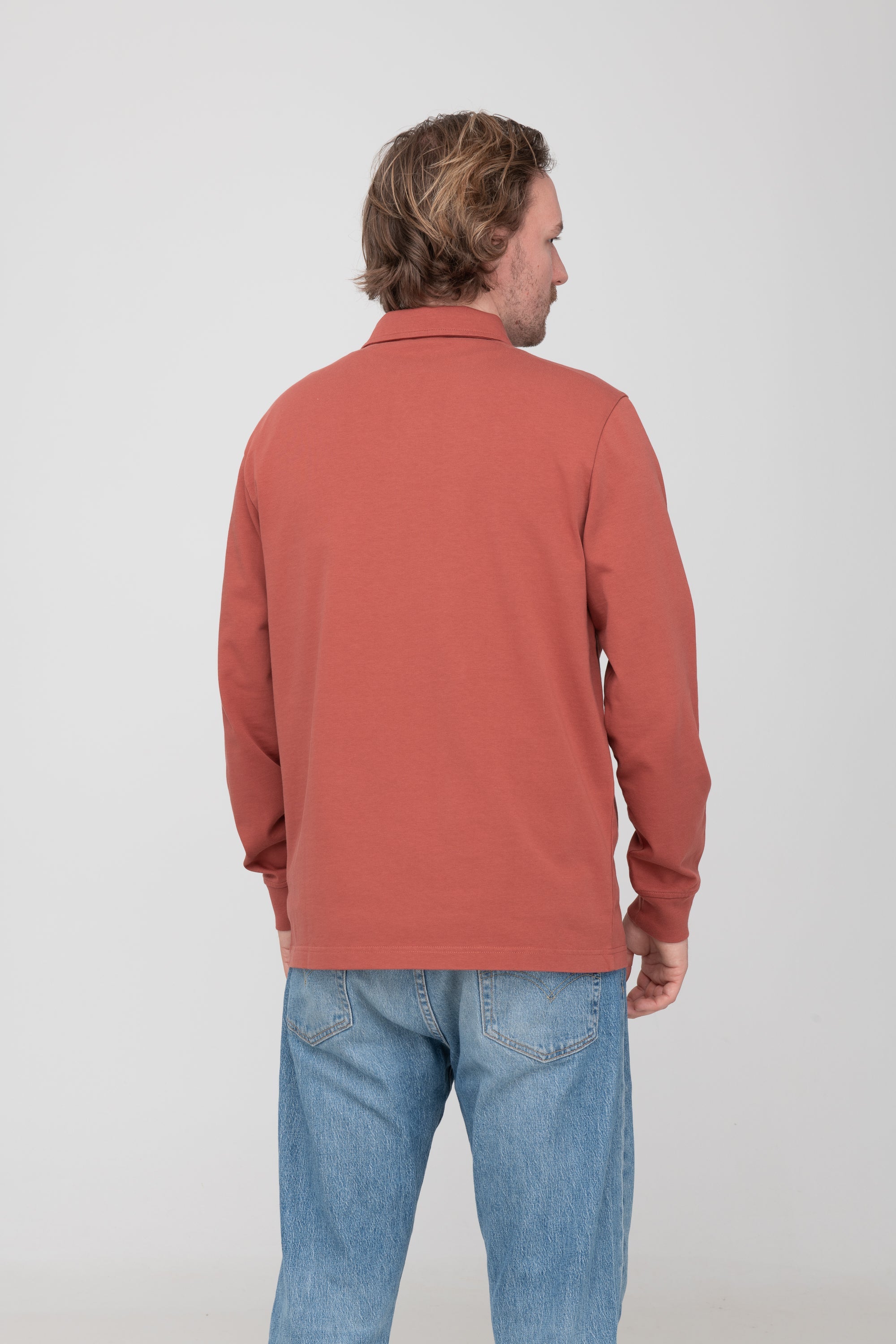 Mann trägt GOTS-zertifiziertes rostrotes Polo Longsleeve von SALZWASSER