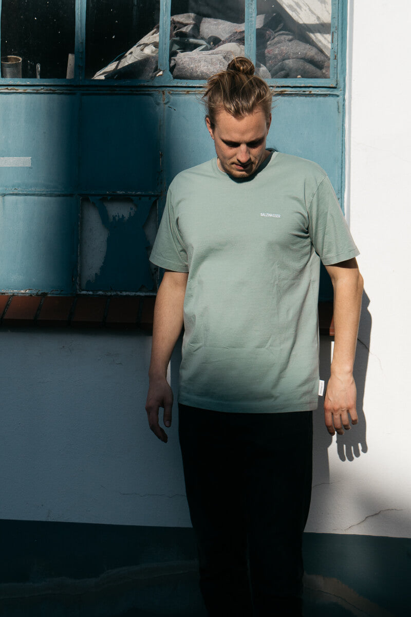 Mann trägt GOTS-zertifiziertes Salbei-farbiges T-Shirt von SALZWASSER